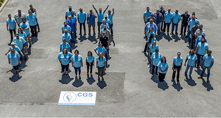 Clearwater employees standing outside in blue forming the number 100
