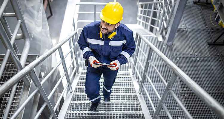 Factory worker or engineer in safety work wear walking through large production plant