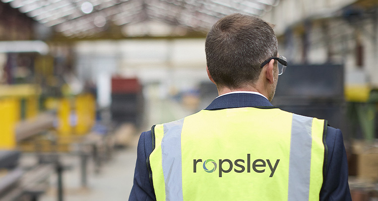 Ropsley worker in yellow high visibility jacket walking away from us.