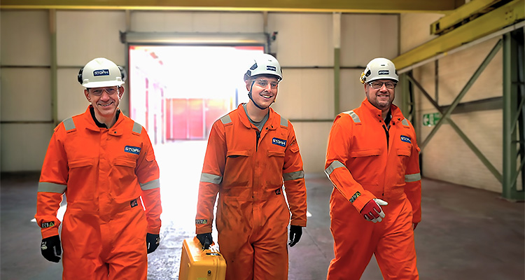 Three Stork worker in orange overalls