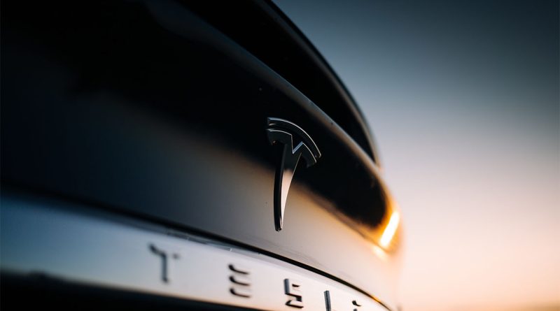 Tesla car with logo showing behind sunset to support Tesla Megapack article
