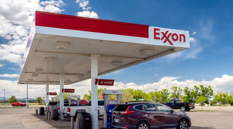 ExxonMobil headquarters sign in front of a modern glass office building with landscaped greenery