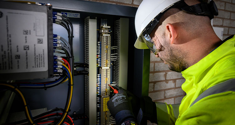 an engineer working on the internal components of a fibre cabinet