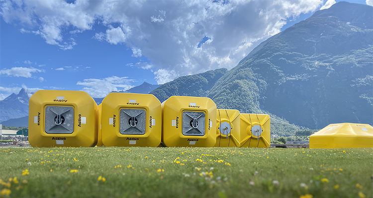 several yellow, square-shaped objects, which are Activa aquaculture buoys, sitting in a grassy field