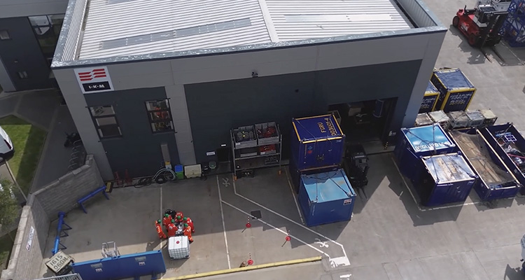 an aerial view of an industrial facility's outdoor yard adjacent to a grey, single-story building