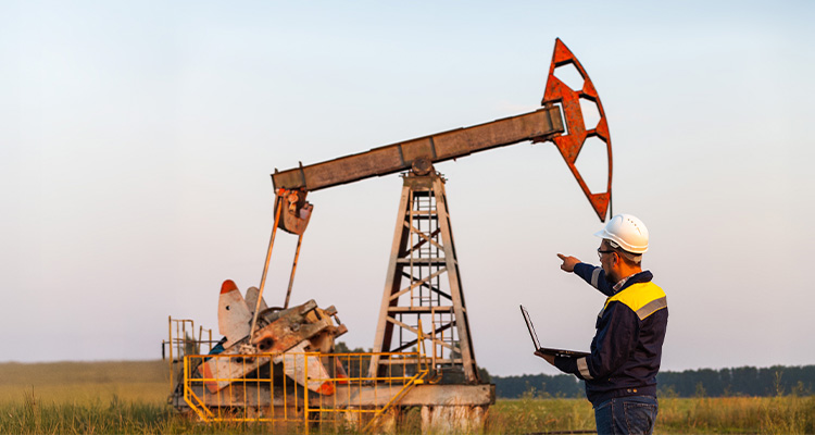 engineer with a laptop on the background of an oil pump