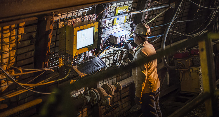 How Becker Mining Systems is shaping the future of underground communications solutions a worker in a mine, interacting with a control panel.